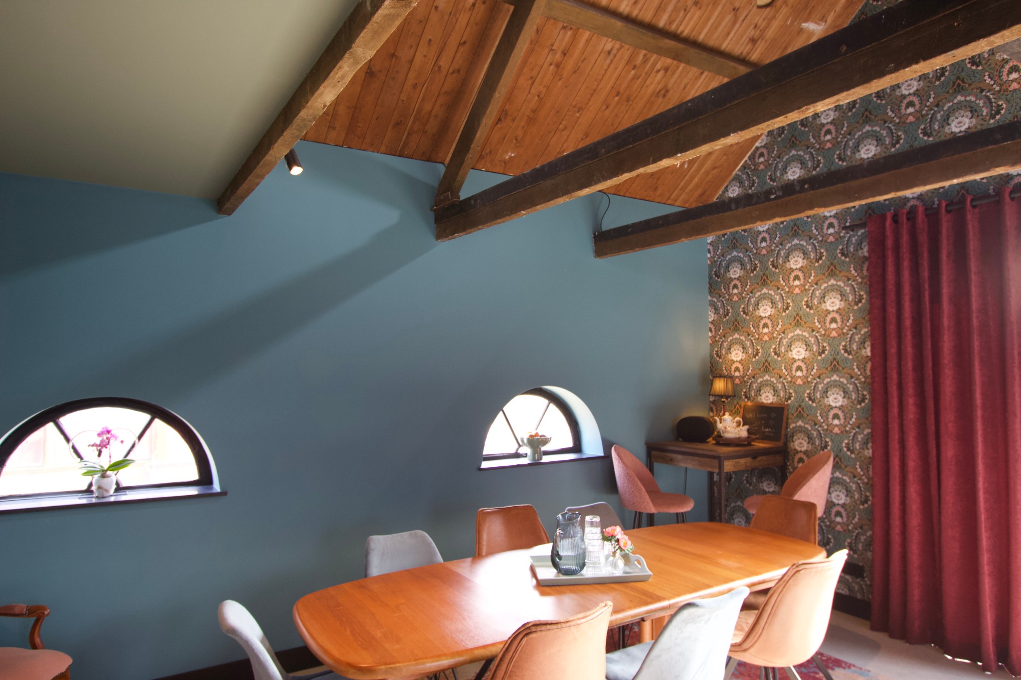Sfeervolle ruimte met houten balken, lange tafel en vintage stoelen